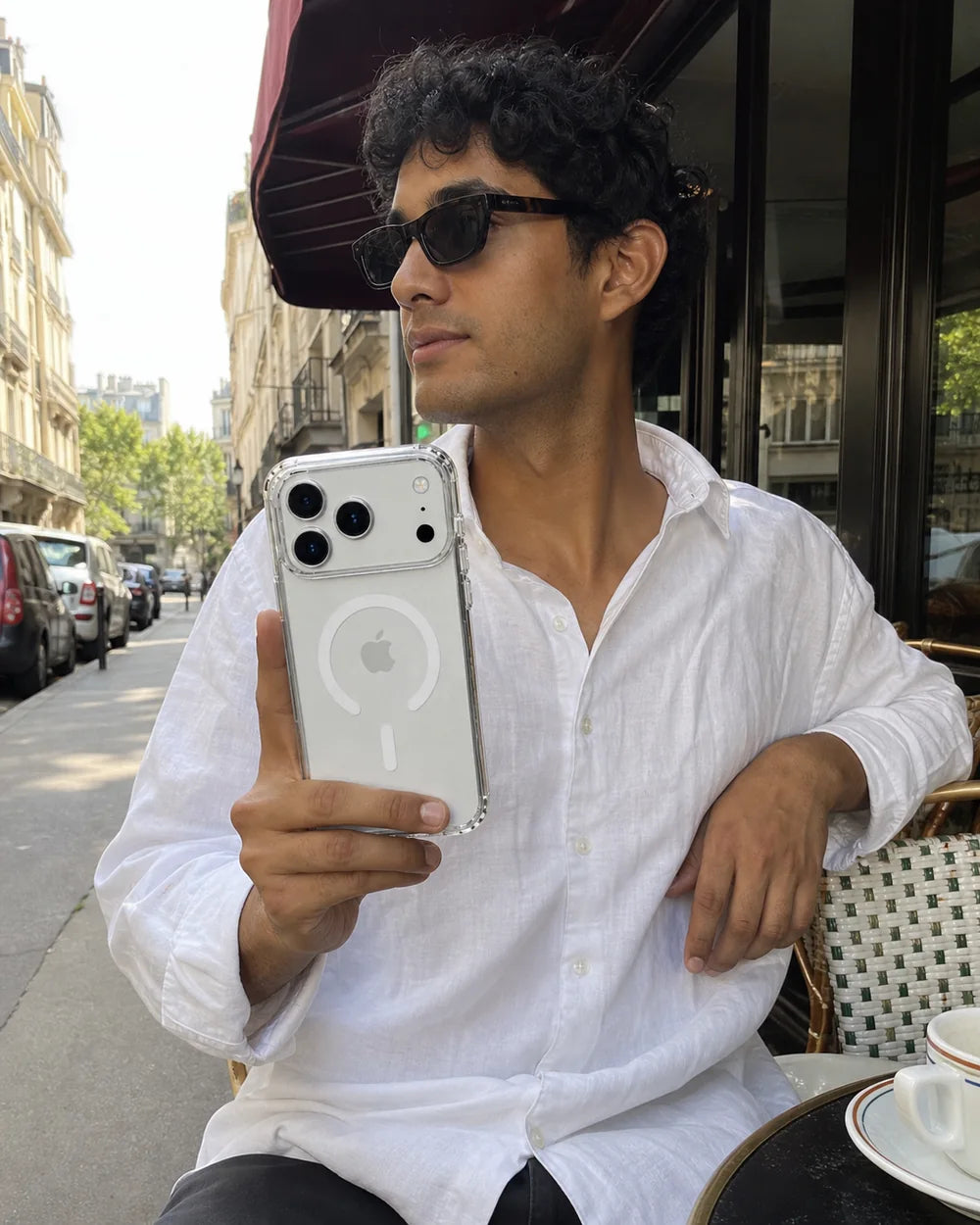 Man using a clear CaseBear iPhone 17 Pro Max case at a sidewalk cafe