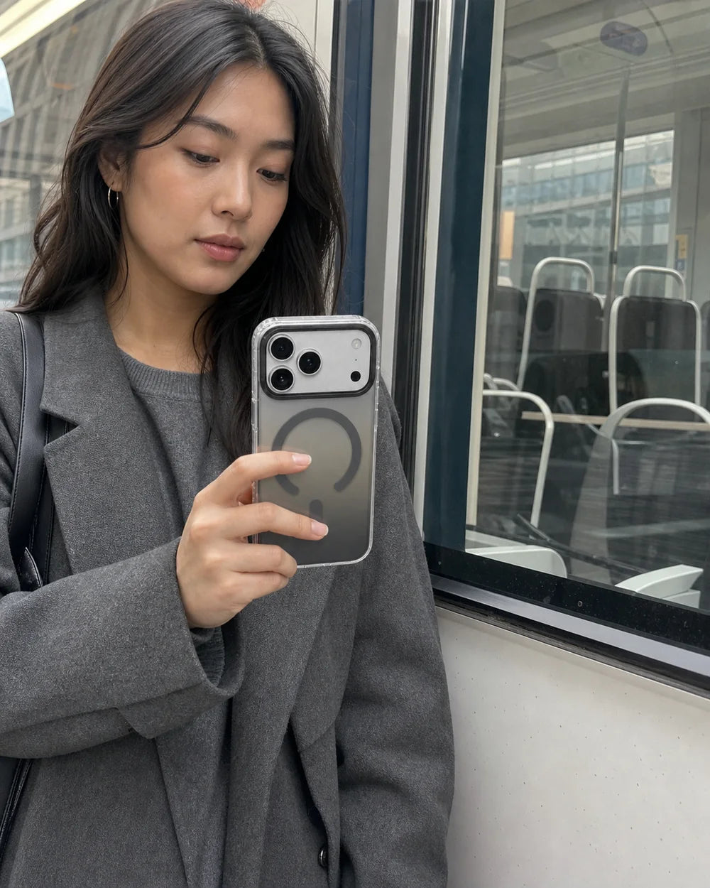 Woman carrying a grey Gradient MagSafe CaseBear case on public transit