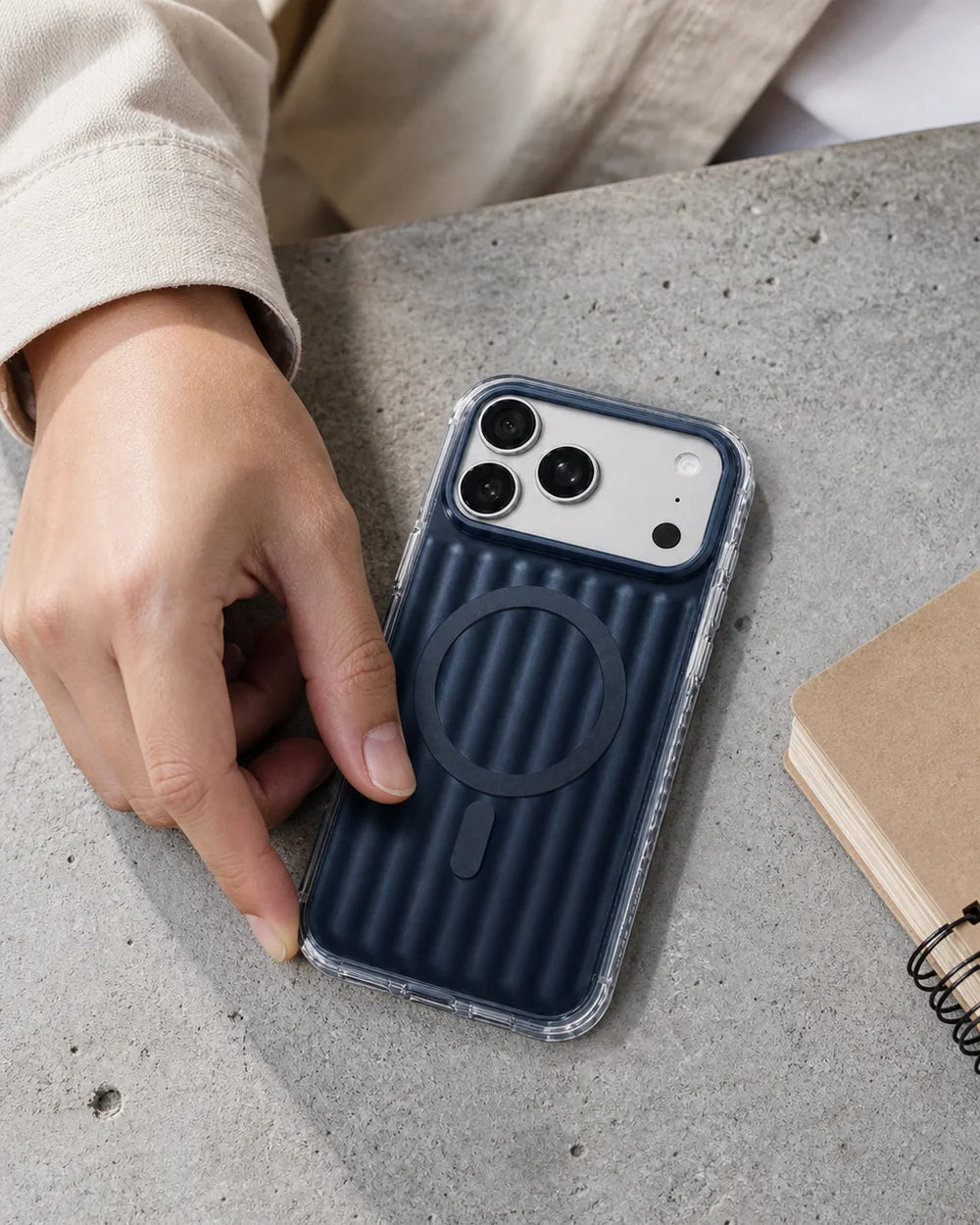 Hand placing a deep-blue Ribbed CaseBear iPhone 17 Pro Max case on a concrete table