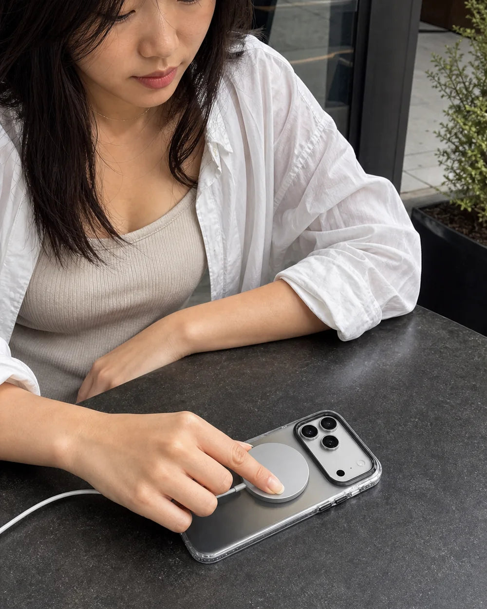 Woman aligning a MagSafe charging puck with a grey Gradient CaseBear iPhone 17 Pro Max case